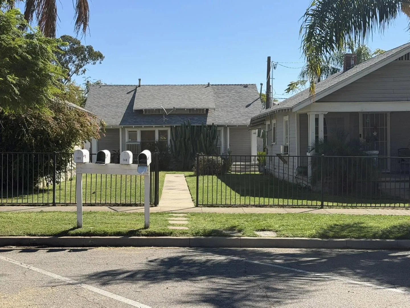 Mowed front lawn behind a black iron fence
